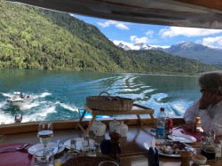 RELAXING IN THE DINING AREA OF PUMA II WHILE MOVING TO ANOTHER LOCATION IN THE LAKE - NOTE SKIFFS IN TOW